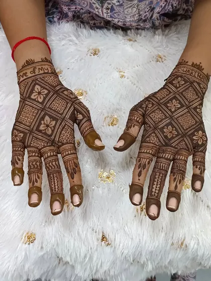 This back-of-hand design features a classic jaal (net) pattern with floral details. The fingertips are left open for a modern touch.