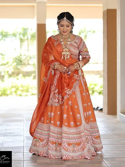 A full-length view of the bride in her stunning rust orange lehenga, looking absolutely regal.