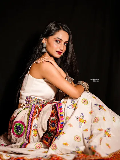 A seated portrait that beautifully displays the full skirt of the embroidered Navratri lehenga, creating a sense of regal grace.