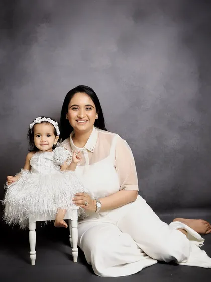 A sweet mother and daughter portrait. The matching white outfits and simple grey background create a timeless and elegant look, highlighting their special bond.