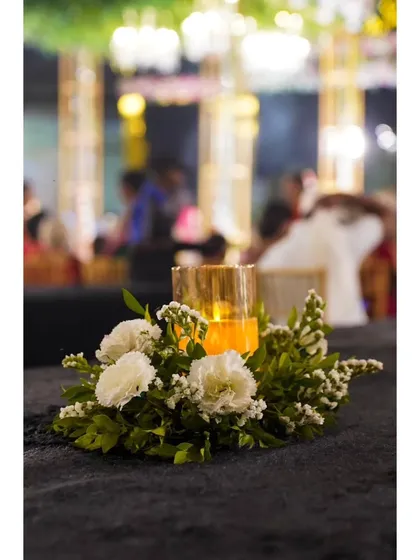 A close-up of a floral centerpiece with a warm, glowing candle. This detail adds a touch of intimacy and elegance to the guest tables.