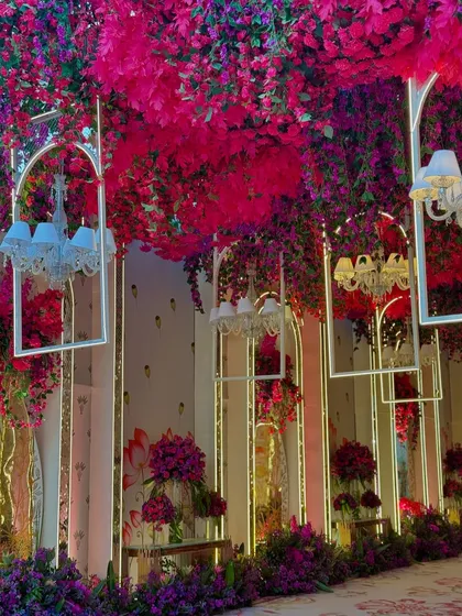 A magical walkway where the ceiling is a canopy of magenta leaves and hanging chandeliers, creating an immersive and luxurious experience for guests.