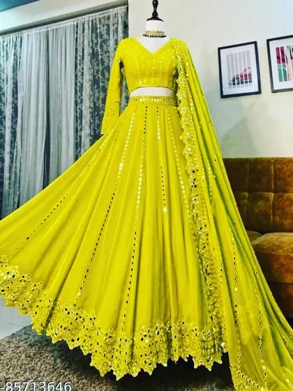 This lightweight georgette lehenga in a stunning lime yellow is perfect for a sangeet or daytime event. The entire outfit is adorned with mirror work and comes with a full-sleeve blouse and a delicate dupatta, offering a bright and glamorous look.