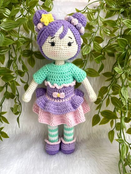 A beautiful doll with purple hair buns and a tutu dress. She also comes with a tiny backpack for her adventures. The striped stockings are attached, but her dress and shoes are removable.