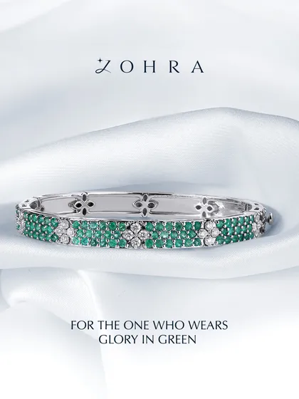 A piece designed to feel like glory in green. This custom bangle is crafted with rows of hand-picked emeralds and brilliant diamonds, set in a floral-patterned white gold band. It's a testament to how we can weave your favourite gems into a design that is both classic and deeply personal.