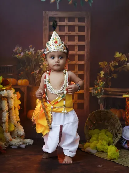 Standing tall and proud, this little toddler is dressed as Krishna. The authentic costume and props help create a powerful and memorable portrait.