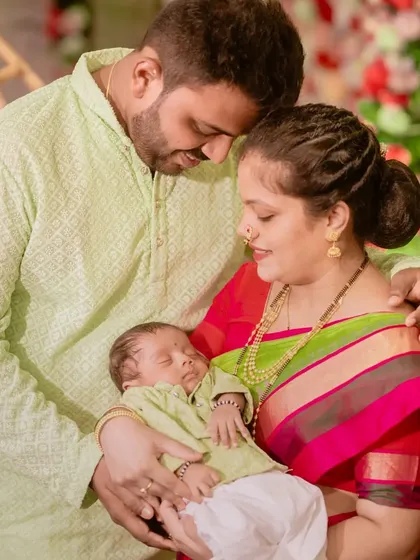 A loving family portrait from a newborn naming ceremony. The parents gaze adoringly at their sleeping baby, a moment of pure love and tenderness.