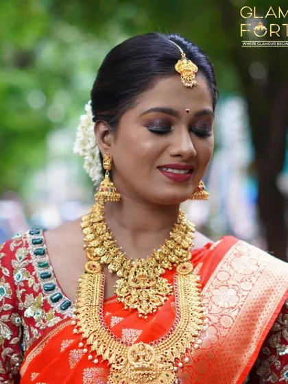 A soft, smiling portrait of a South Indian bride. The eye makeup is kept subtle and shimmery to let the bold lip colour and heavy jewellery stand out.