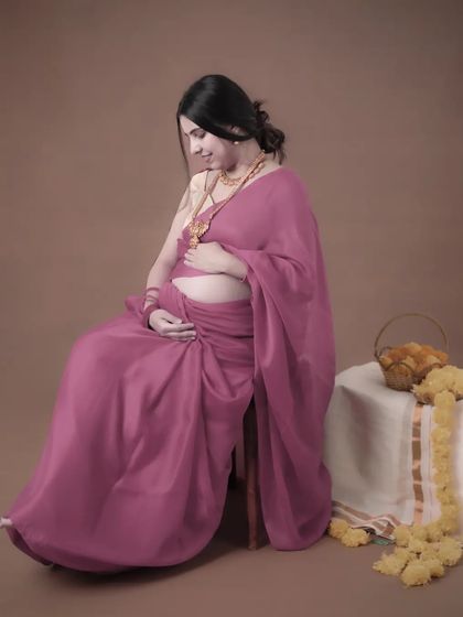 A quiet moment of connection between a mother and her unborn baby. Seated gracefully in a pink saree, she looks down at her bump with love and anticipation.
