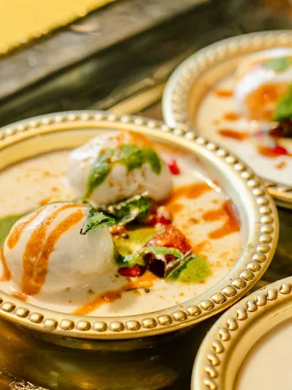 A close-up of the Dahi Vada from our Jain thaali, perfectly soft and soaked in creamy yogurt, garnished with sweet and spicy chutneys.