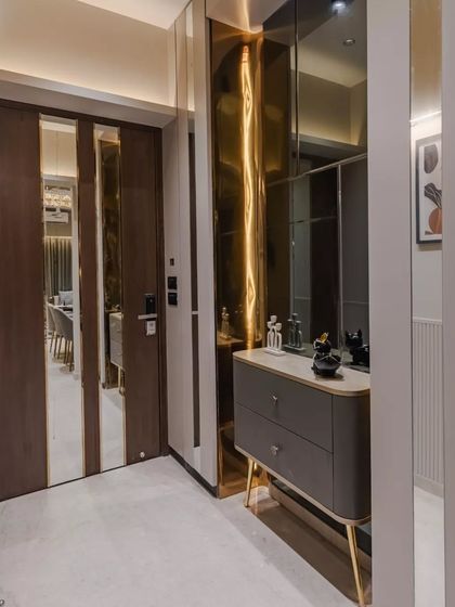 Step into elegance with this stunning foyer design, where a harmonious blend of rich wooden doors, mirrored panels, and luxurious golden accents creates a captivating first impression.