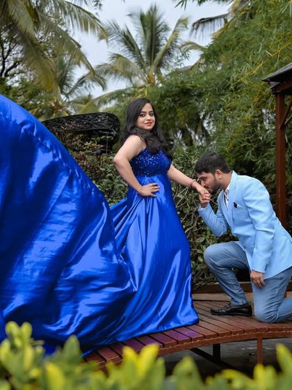 A tender proposal-style moment on the wooden bridge, with the flowing blue gown adding to the drama.