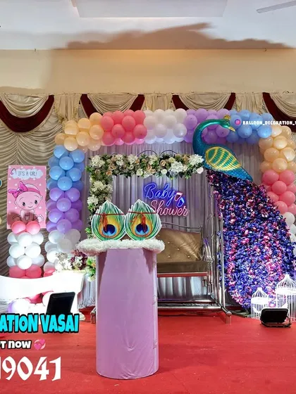 A grand baby shower in a hall featuring a large peacock, a crescent moon photo prop, and multiple balloon pillars. This setup shows how I can fill a large stage with many fun and colorful elements.