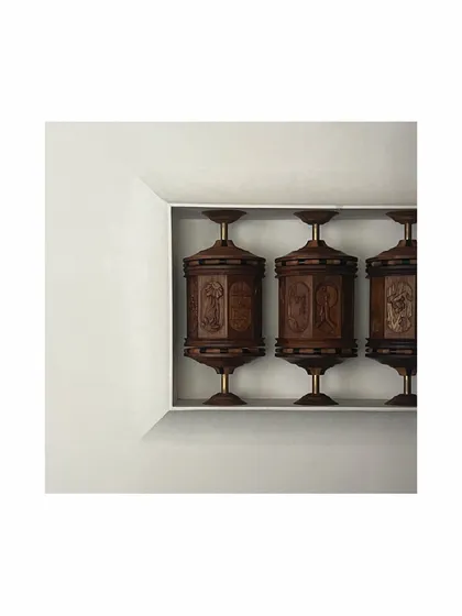 A different angle of the Buddhist prayer wheel-inspired sculpture. Set within a clean, white niche, the intricate carving and warm wood of the wheels stand out, turning a simple passageway into a gallery-like experience.