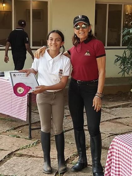 A camper proudly displays her certificate alongside her instructor. The bond formed between students and teachers is a special part of the camp experience.