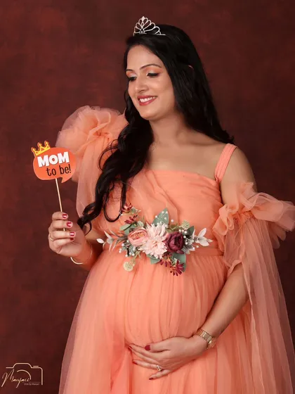 A princess moment. Wearing a delicate tiara and a flowing peach gown, this mama-to-be looks absolutely radiant and full of joy.