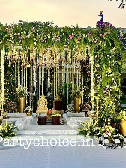 Here is a front-facing view of our grand peacock-themed mandap. The structure is covered in greenery and flowers, with hanging floral strings and chandeliers creating a magical effect, all centered around the ornate couple's seating.