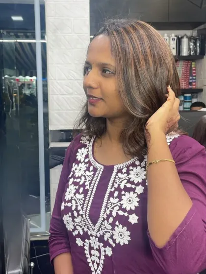 A happy client showing off her new shoulder-length cut with soft layers and highlights.