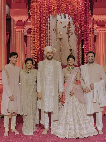 A formal portrait of Shivam and Tanya with his family. The coordinated outfits and the grand backdrop create a regal and elegant image of the newly expanded family.