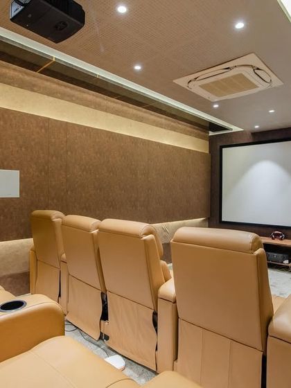 The home theatre in the "Chic Adobe" project, with comfortable leather recliners and acoustically treated walls for a professional cinema experience at home.