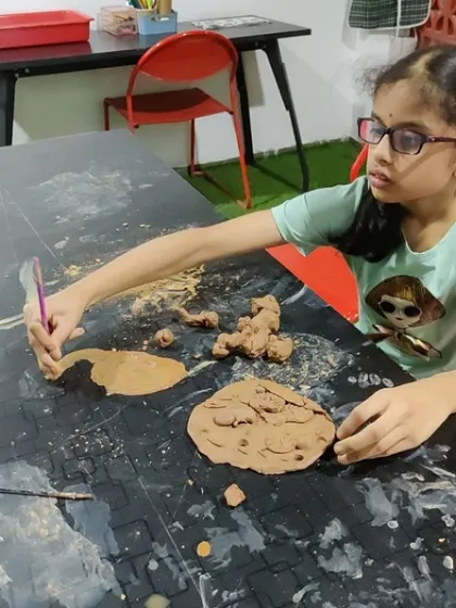 A young girl painting with clay, fully engaged in the sensory experience. These moments of quiet focus are where creativity and self-discovery happen.