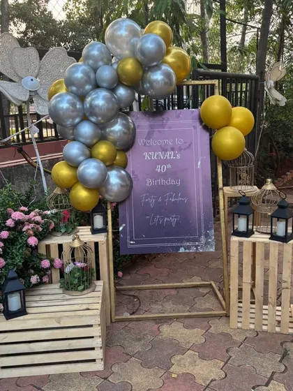 Welcome your guests in style with a personalized entrance sign. For this 40th birthday, we designed a custom welcome board and decorated it with a classy gold and silver balloon arrangement, lanterns, and wooden crates for a rustic yet elegant feel.