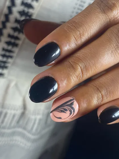 A bold and elegant set with glossy black nails and a nude accent nail with abstract art.