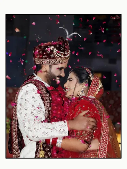 The peak of the celebration during the varmala ceremony. This candid shot captures the couple sharing a laugh amidst a shower of petals, a perfect example of the joyful chaos we love to document.