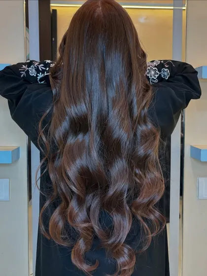 The back view showcases the length and health of the hair, enhanced by the rich copper brown shade.