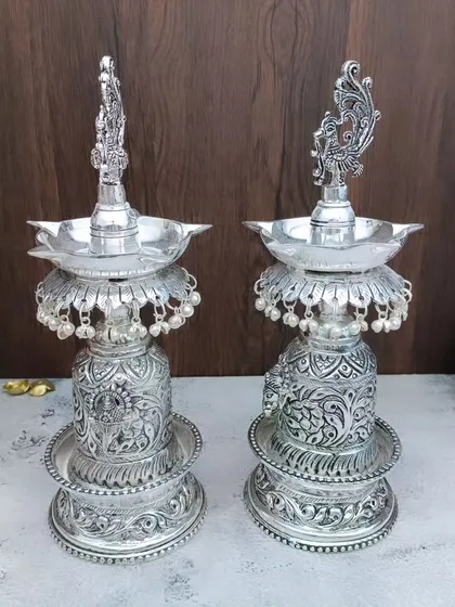 A pair of antique German silver Hamsa designer diyas, featuring intricate carvings and small hanging pearls for a grand look.