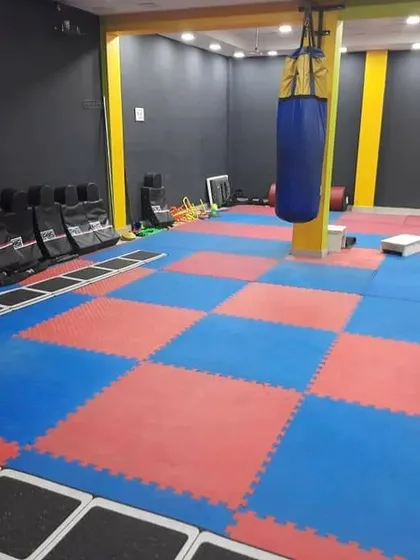 A clear view of our matted training floor, or dojang. It is equipped with punching bags, kick pads, and agility ladders for a complete martial arts training session.
