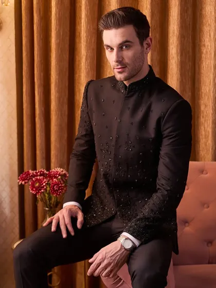 A seated portrait showing the impeccable fit of the black embellished bandhgala. It's a powerful, confident look for any formal evening occasion.