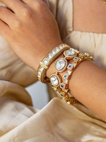 A close-up of a bride's wrist, adorned with a stack of beautiful Kundan and Polki bangles.