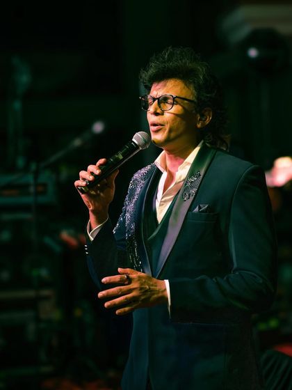 A close-up of Abhijeet Sawant, showing the detailed embroidery on the lapels of his tuxedo jacket as he performs.