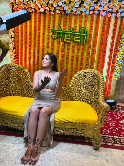 A happy bride at her mehndi ceremony, with a beautiful setup and my henna on her hands.
