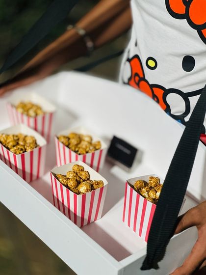Salted caramel popcorn served in classic striped boxes. We offer fun and creative food service options, like these pass-around trays, to match the theme of any party.