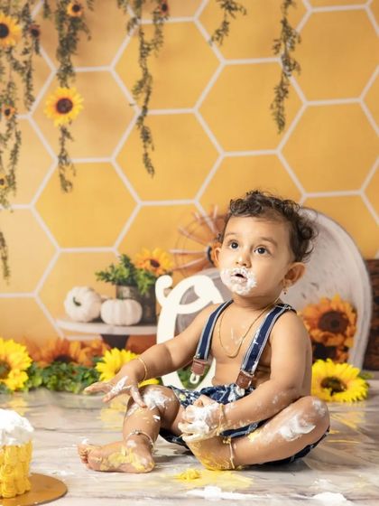 The aftermath of a successful cake smash. This little one is covered in frosting from head to toe, a perfect memory of a fun-filled first birthday celebration.