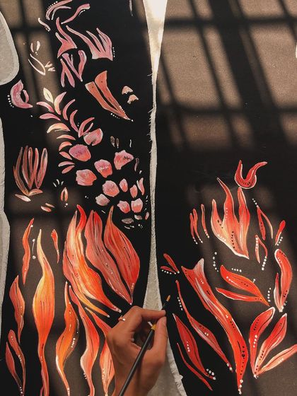 A wider shot of me painting the abstract fire patterns on the two panels of a tuxedo before they are stitched together.