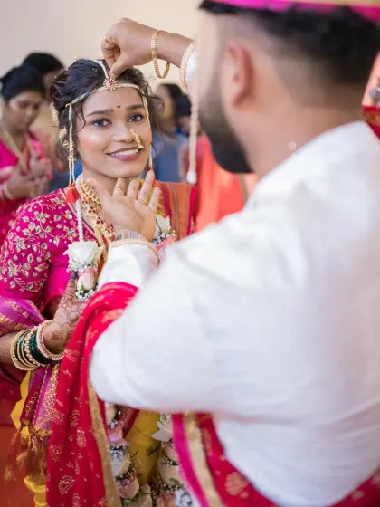 The groom applies the sindoor, a poignant and symbolic moment in the wedding ceremony. The bride's gentle smile makes this shot incredibly special.