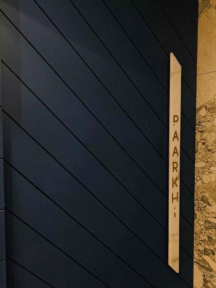 A close-up of the specially curated door handle for Paarkhi. The brand name is engraved into marble and finished with golden paint, a small but significant detail that communicates luxury and craftsmanship from the first touch.