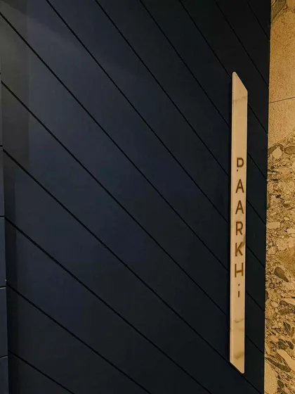 A close-up of the specially curated door handle for Paarkhi. The brand name is engraved into marble and finished with golden paint, a small but significant detail that communicates luxury and craftsmanship from the first touch.