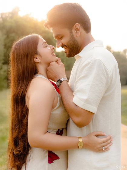 A sweet portrait capturing the groom's affectionate gesture and the bride's happy reaction in the warm sunlight.