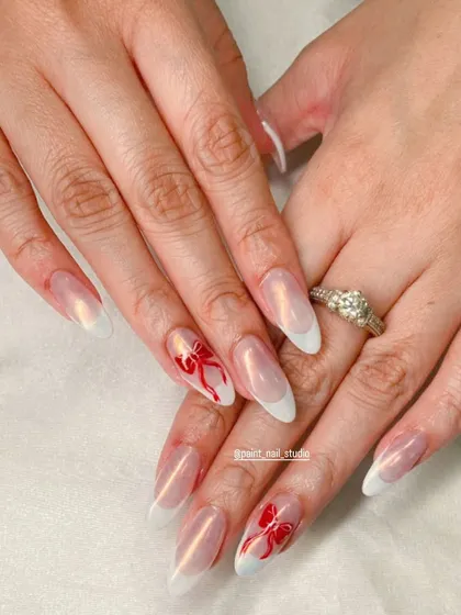 A simpler, yet equally beautiful Christmas look. This features a classic white French manicure on a shimmery base, with two accent nails padrões with hand-painted red bows.