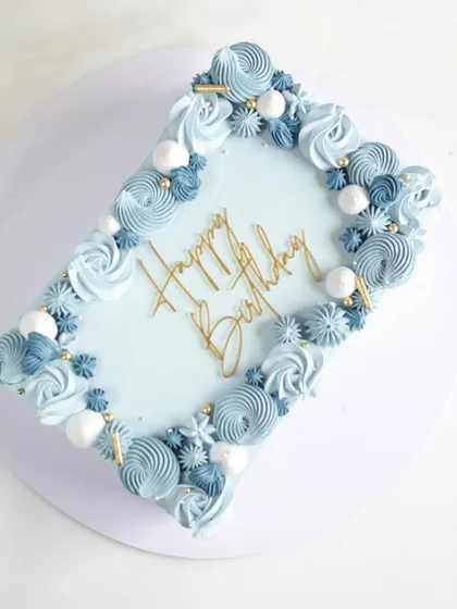 This rectangular sheet cake was for a 60th birthday, decorated in a beautiful blue ombre. The border is piped with intricate swirls and rosettes, creating a simple yet stunning celebration cake.