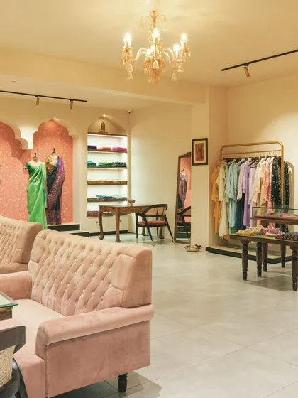 This angle highlights the comfortable tufted sofas and the main saree display in the background. The design provides a luxurious and personal shopping environment for customers.