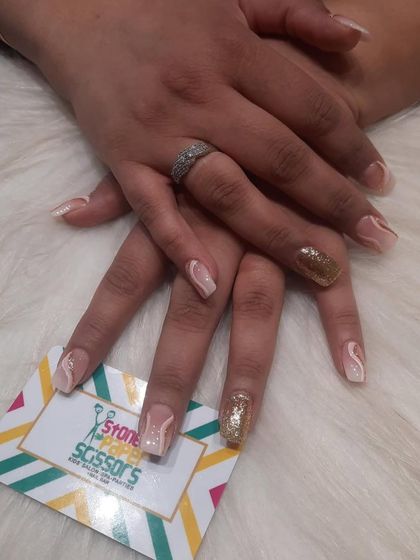 An elegant nude manicure with a touch of glam. This set features delicate white swirls on a nude base, with a single, full-coverage gold glitter accent nail for a pop of sparkle.