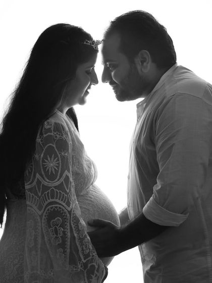 A high-contrast, black and white silhouette. This artistic shot captures the intimate moment before a kiss, focusing on the profiles and the connection between the couple.