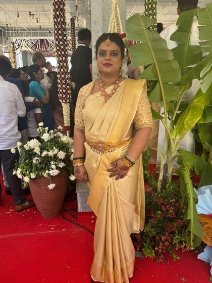 A client at a wedding, wearing a classic gold Kanchivaram saree with a matching hand-embroidered blouse.