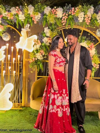 A lovely photo of the couple against the modern gold and floral backdrop, capturing the happy atmosphere of their Sangeet celebration.