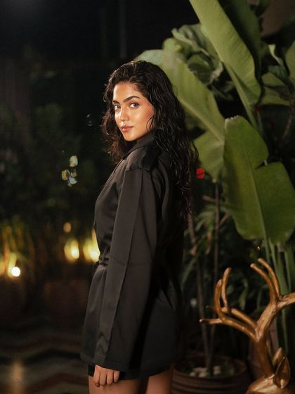 A beautiful portrait taken amidst lush greenery at night. The soft backlighting separates the model from the background, creating a gentle and flattering glow.